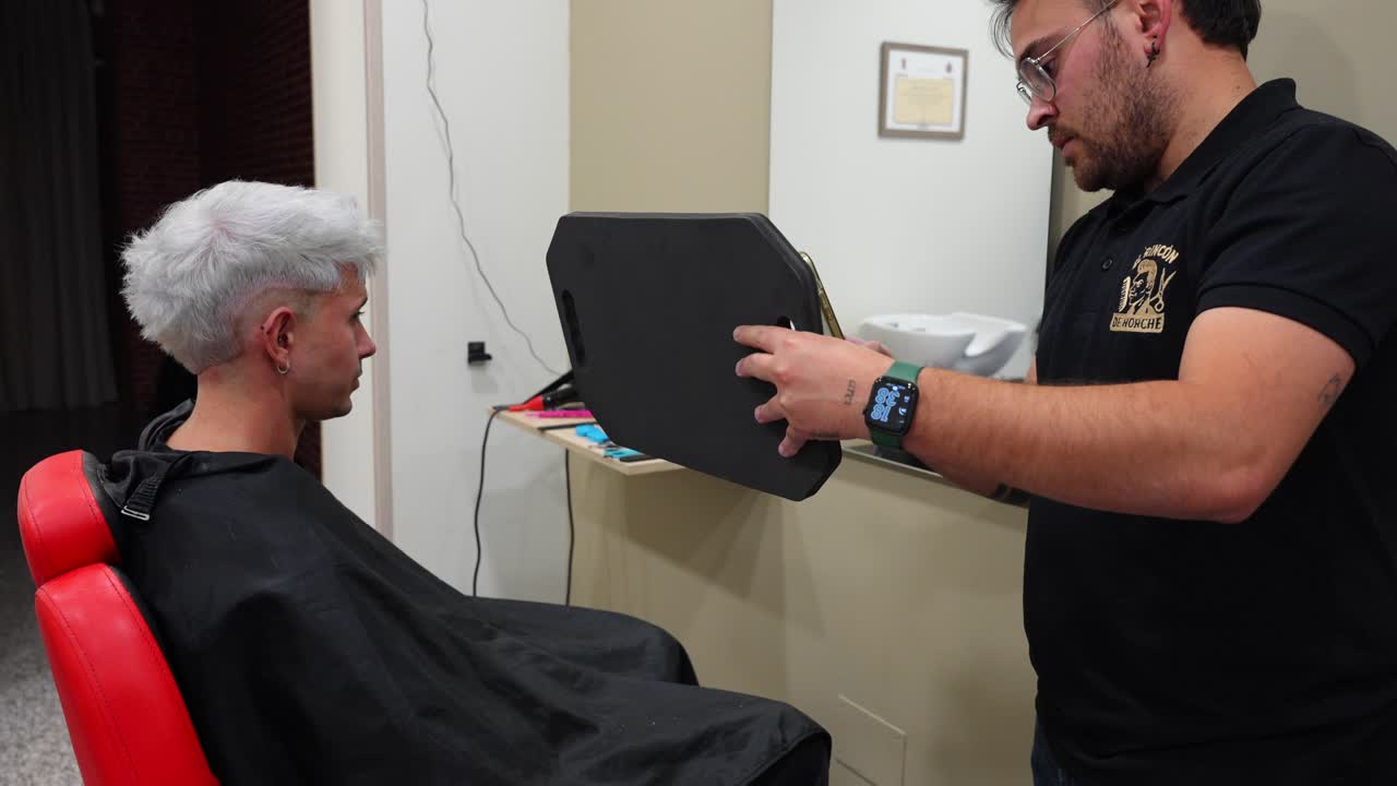 Proud hairdresser takes photo of mirror reflection showing customer’s final hair colour after bleaching