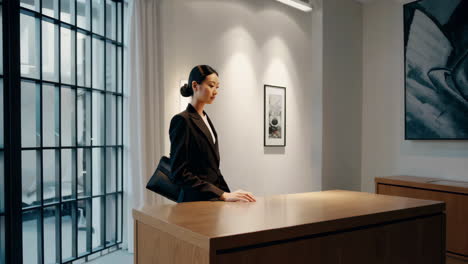 a professional asian woman checking her watch in a modern office or lobby