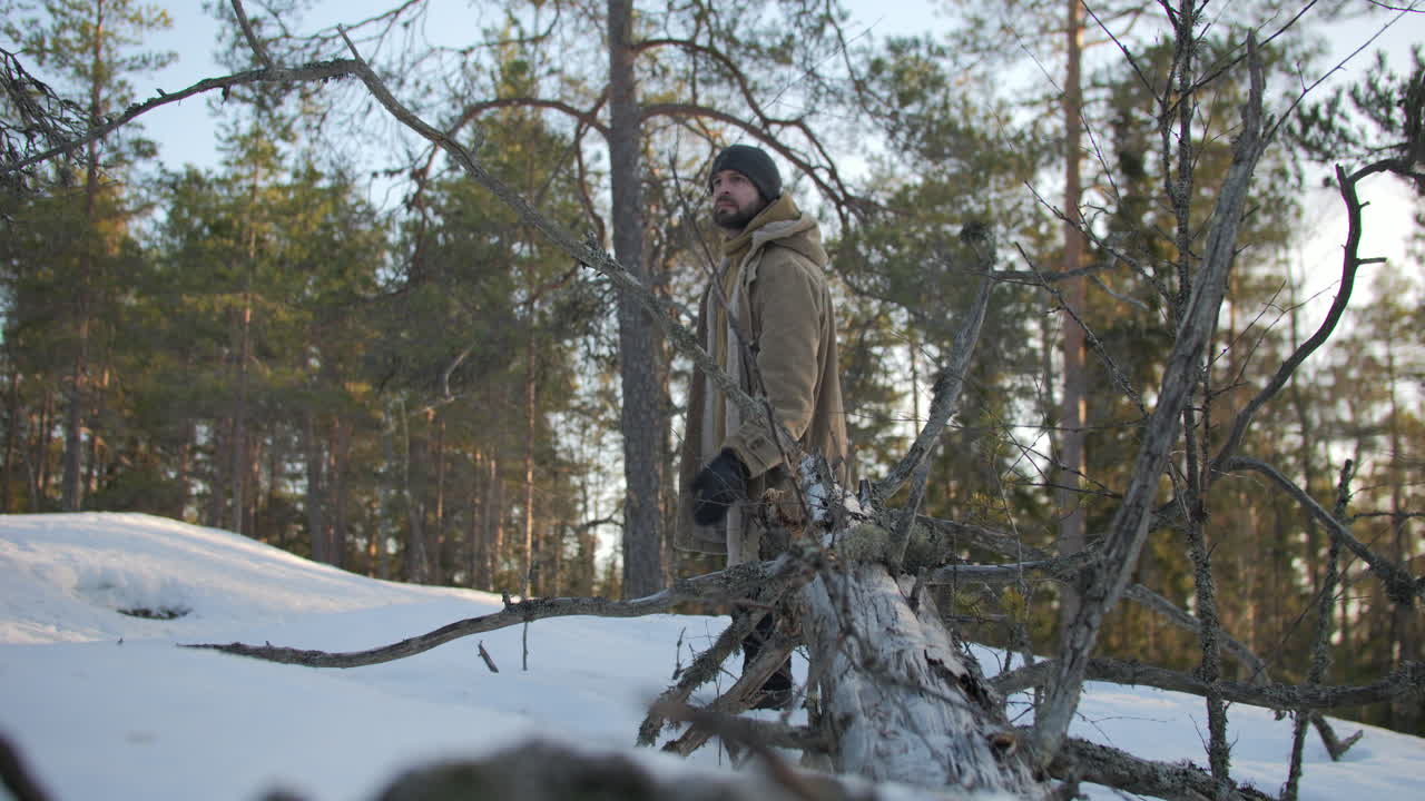 hombre feliz caminando en el bosque de invierno y toca el árbol caído, vista estática