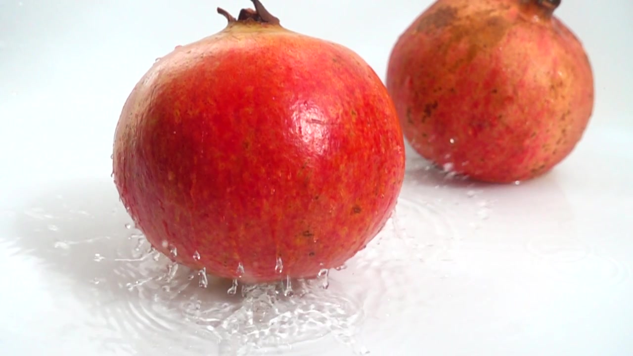 Granatæble falder i vandet. Slow motion