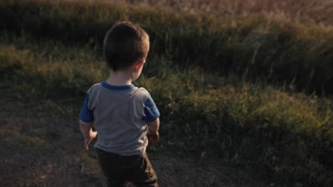 a young, happy boy playing outside and throwing dirt in sunset in cinematic slow motion