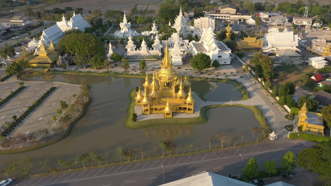 drone aéreo al revés de wat rong khun el templo budista gigante blanco y el templo dorado con montañas y paisaje en chiang rai, tailandia