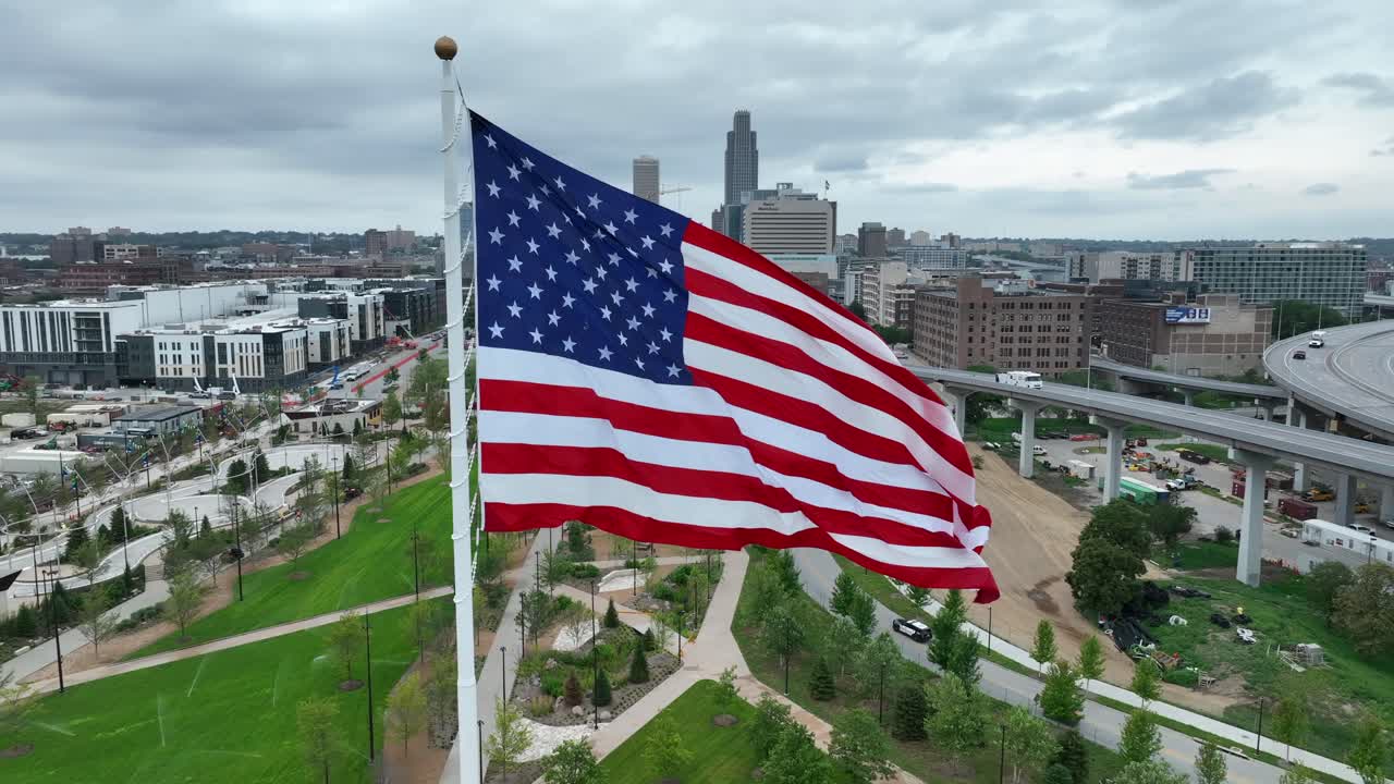 Bandiera americana che sventola in alto sopra i parchi sul lungofiume e lo skyline di Omaha.