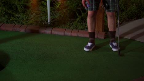 a golfer enters the course for his turn dropping a purple ball on the ground and lining up his shot