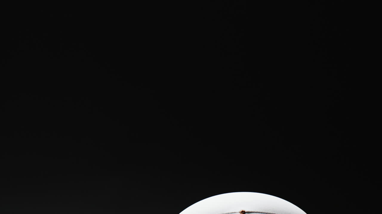White rugby ball on black background with copy space, slow motion