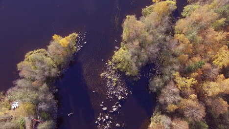 Imágenes-Aéreas-De-Un-Río-Con-Tres-Barcos-En-Tierra-Y-Un-Entorno-Forestal-De-Colores-Otoñales