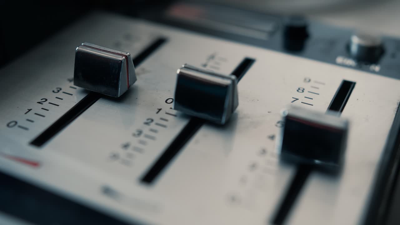 Close-up de mão ajustando faders em uma mesa de som