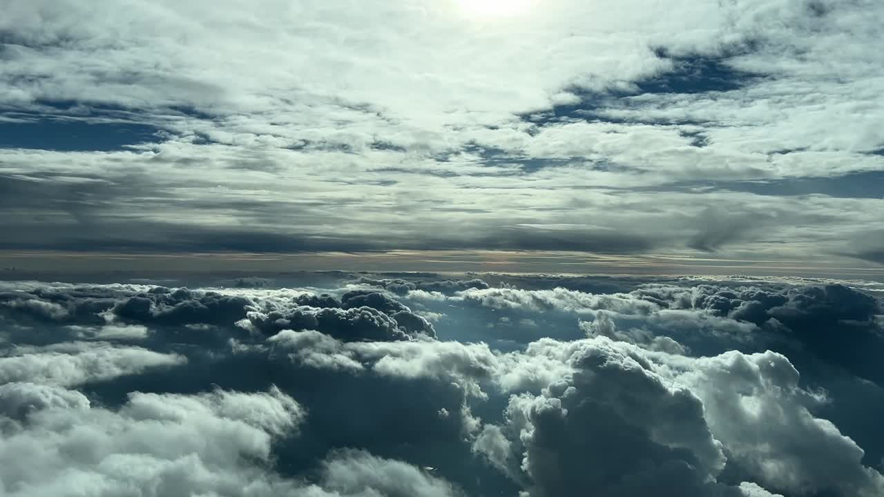 vista de cabina de un cielo nublado volando entre capas de nubes blancas, negras y grises durante la puesta de sol