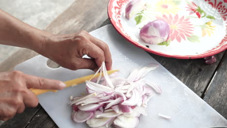 top view person using knife to slice red onions on white cutting board