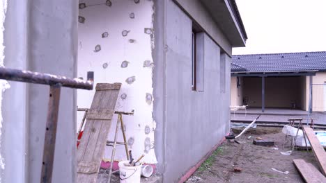rear side of house showing unfinished insulation and scattered construction tools