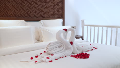 swan towels with red rose petals on bed - romantic room setup at luxury hotel in bali, indonesia