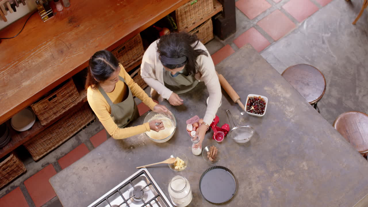 Multiracial grandma and young woman baking together in kitchen, preparing dessert, at home