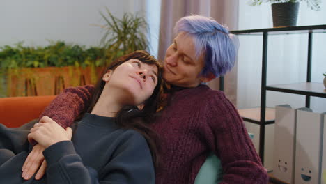 loving same sex female lesbian women family couple hugging, relaxing together, lie on sofa at home