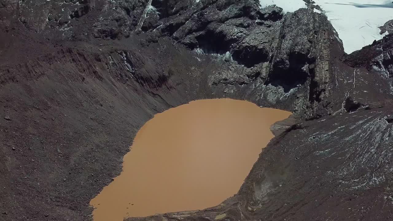 aereo, inclinare verso l'alto, drone girato sopra un lago di acqua marrone sotto montagne innevate, nella regione di cusco, ande, perù - giornata di sole
