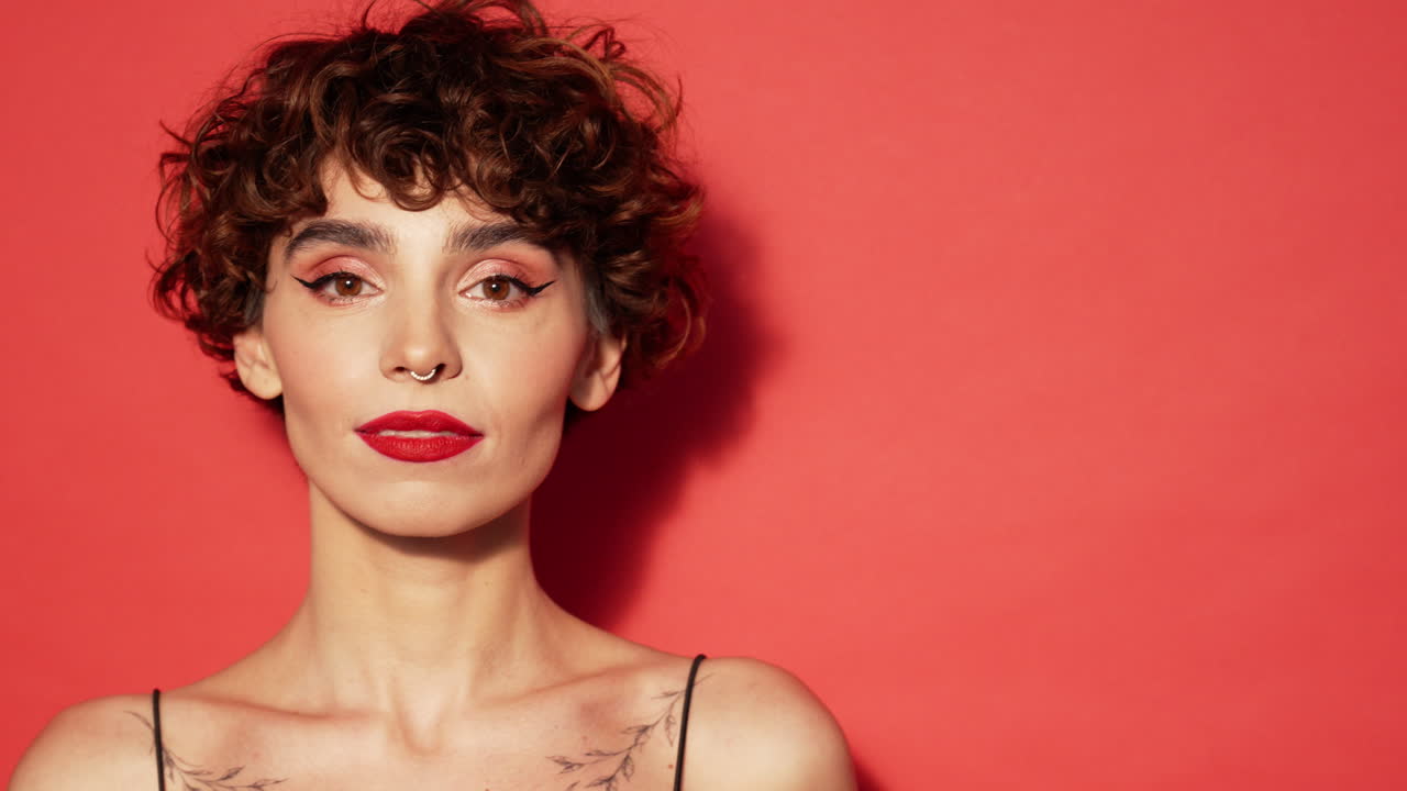 Donna con capelli ricci e trucco su sfondo rosso