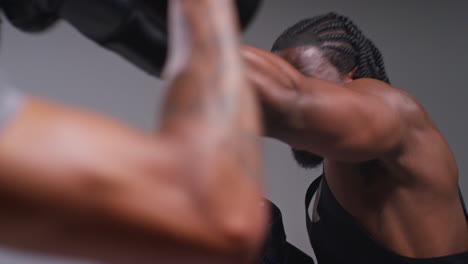 Close-Up-Shot-Of-Male-Boxer-Sparring-Working-Out-With-Trainer-Wearing-Punch-Mitts-Or-Gloves-Practising-For-Fight