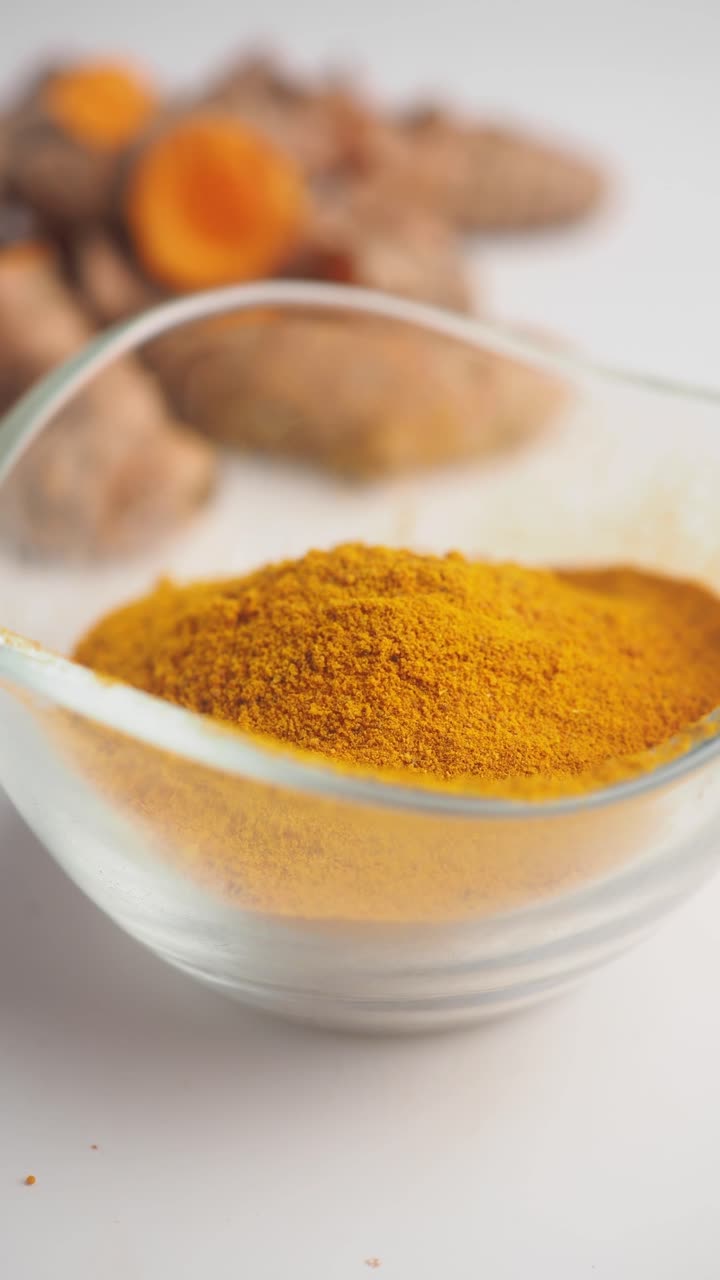Turmeric Powder in Glass Bowl with Fresh Roots