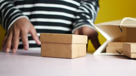 person preparing small brown gift boxes for shipping