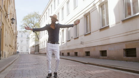 happy afro caribbean man with panama hat dancing latin dance alone in the old town street