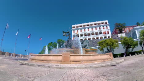 Dolly-shot-of-the-roots-fountain-at-Od-San-Juan,-Puerto-Rico-with-buildings-behind-it