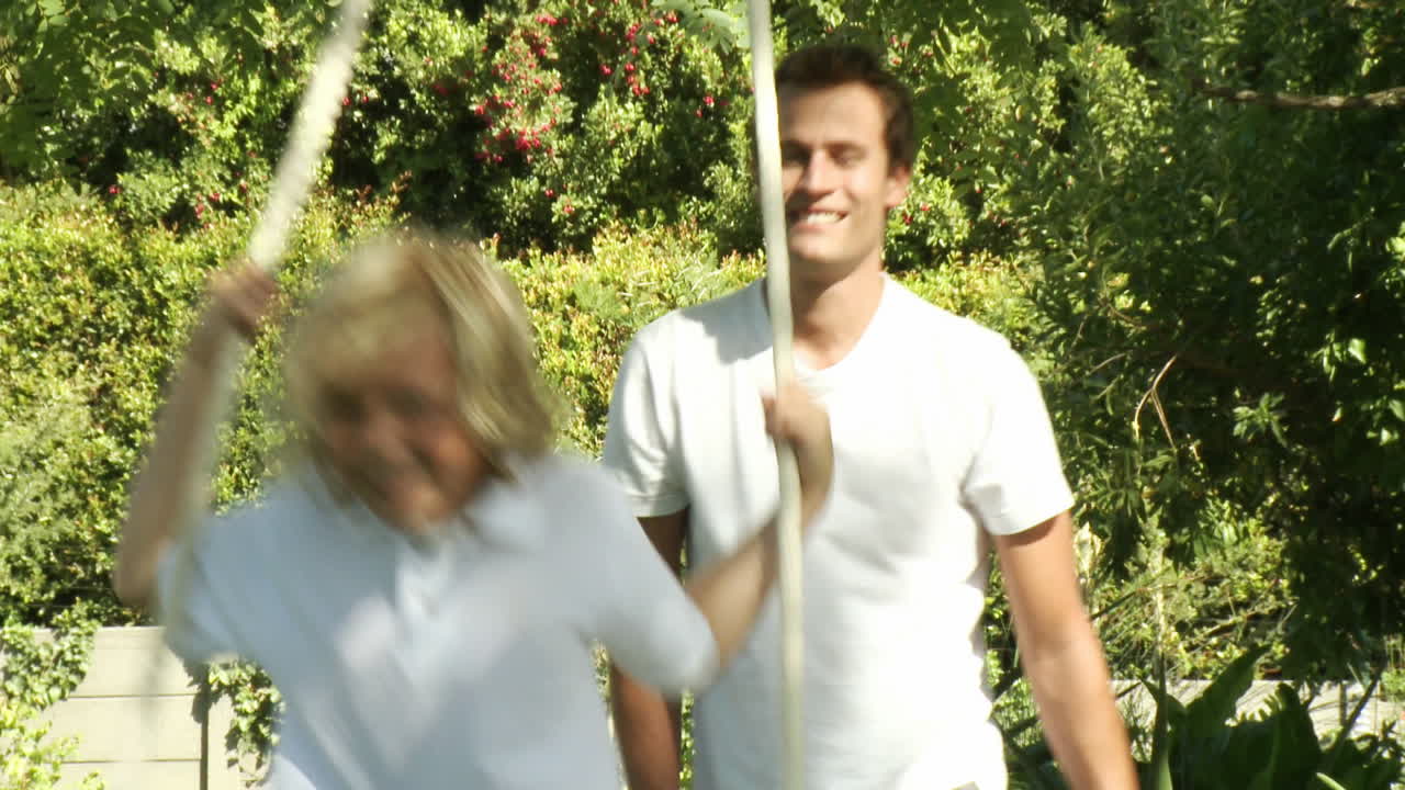 padre orgulloso empuja a su hijo en un columpio