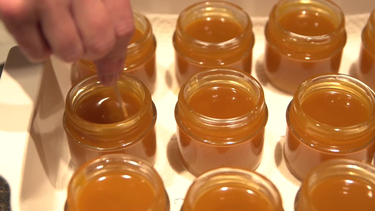 나무 막대기로 짙어지는 황금 cbd 주입 고약을 저어줍니다.