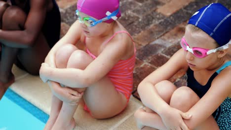 lindos niños sentados cerca de la piscina
