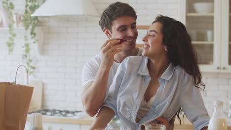 una joven pareja casada coqueteando en la cocina de su casa.