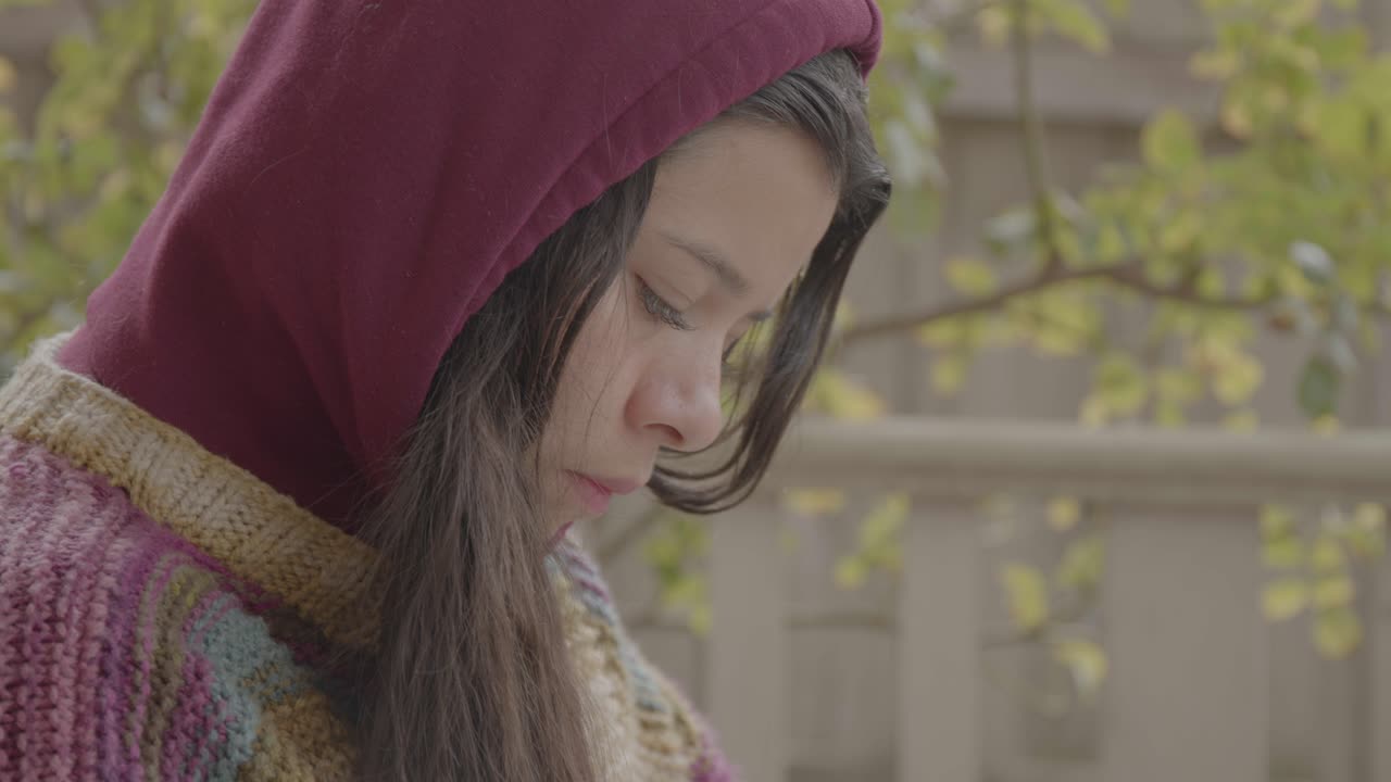 Hispanic latino woman in knitted sweater and hoodie reading the bible with cross, thinking face expression, Side profile, Tilt up shot