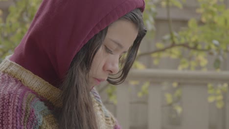 hispanic latino woman in knitted sweater and hoodie reading the bible with cross, thinking face expression, side profile, tilt up shot