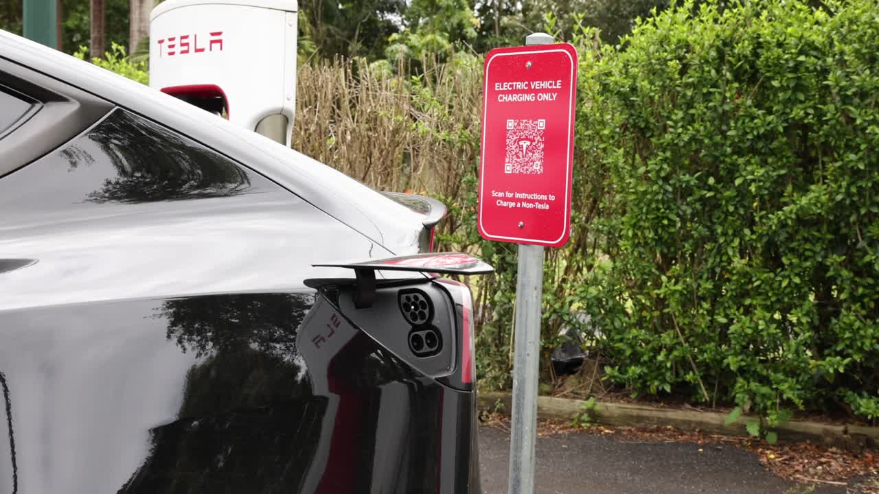 el vehículo de tesla se acerca y se estaciona en una estación de carga