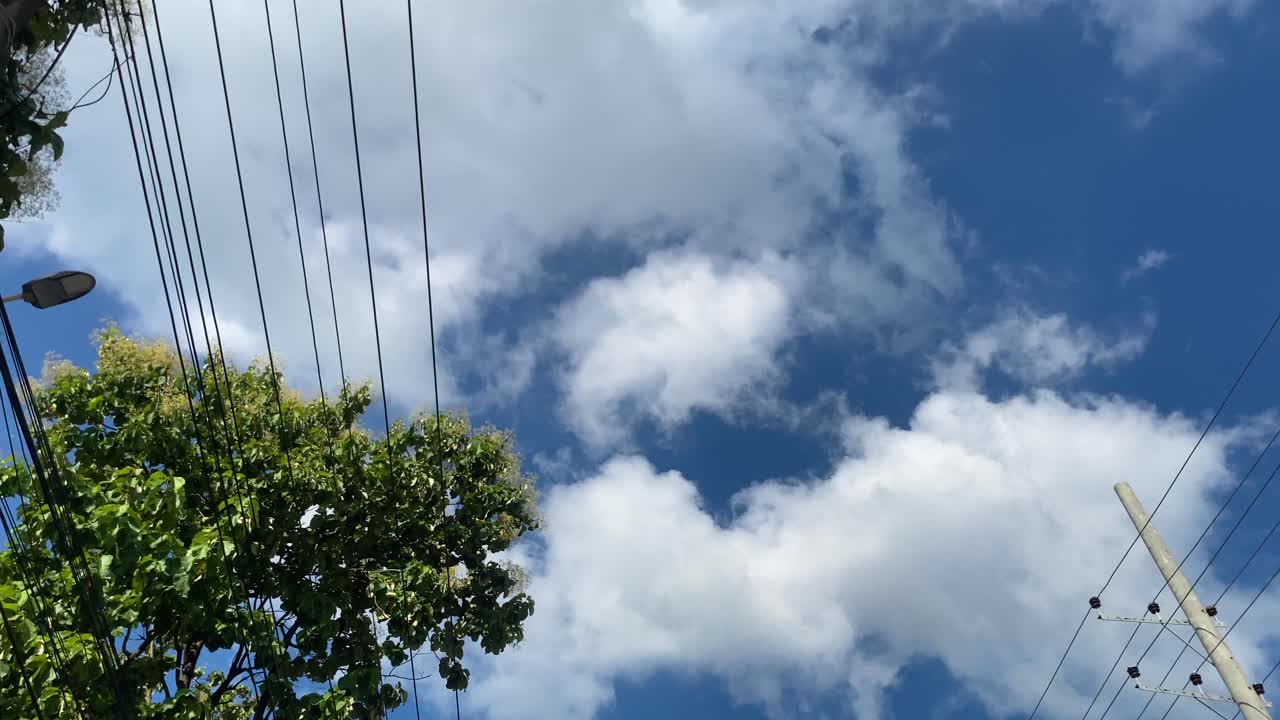 Blue sky with white fluffy clouds and electric wires