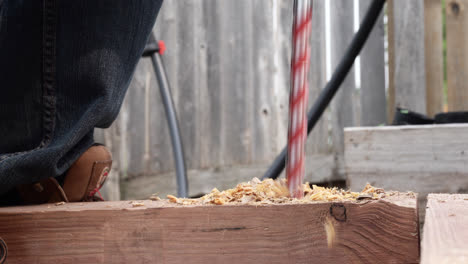 Close-Up-Of-A-Metal-Drill-Bit-Making-A-Big-Hole-In-Wooden-Plank