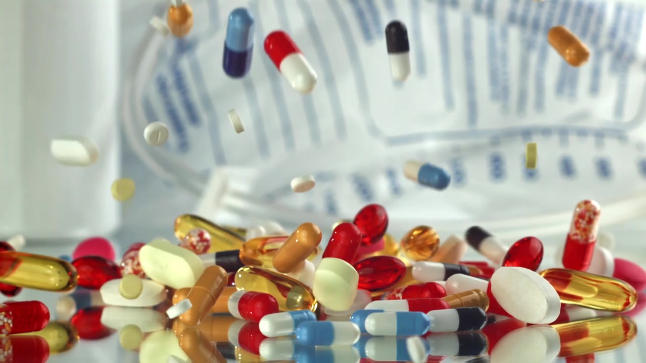 Colorful Pills and Capsules Falling onto a Reflective Surface