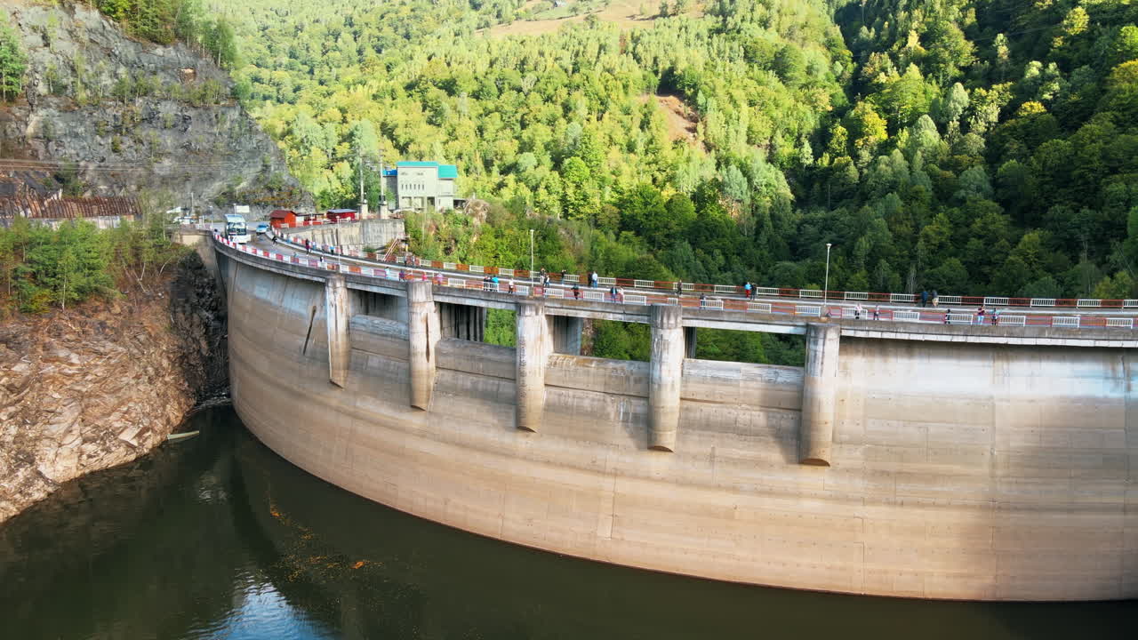 Aerial drone view of a Dam at the Taul Bistra lake in Romania. Carpathian mountains, hills with lush forest, multiple visitors