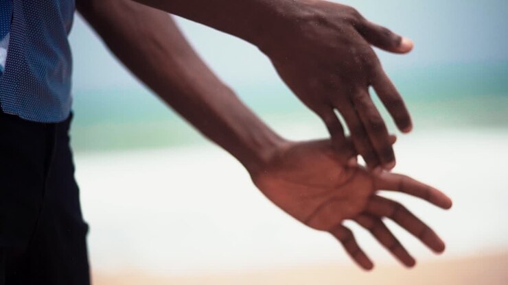 rapprochement au ralenti de mains masculines méconnaissables secouant et tapant du sable après un dur travail
