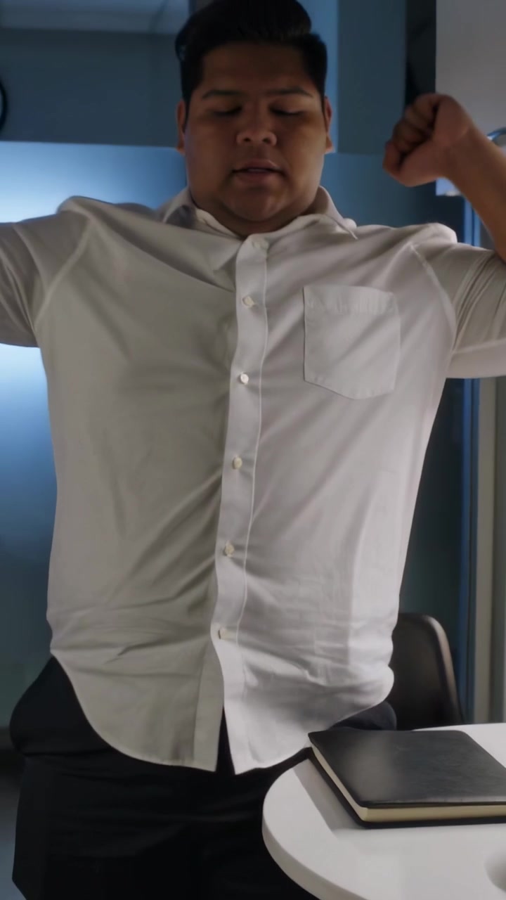Video verticale: Uomo in camicia bianca che chiude un blocco a spirale, si alza, si stira ed esce dall'ufficio.