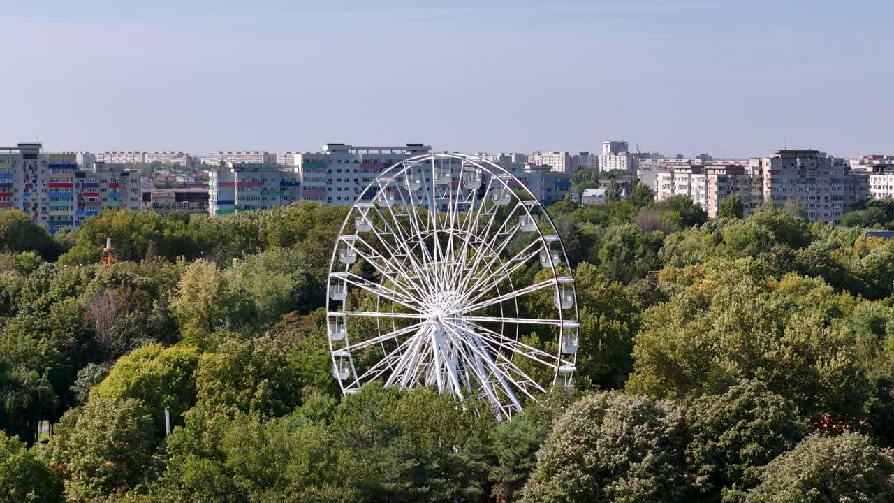 Rotating Aerial View of a White Ferris Wheel Surrounded by Oraselul Copiilor Park in Bucharest, Romania