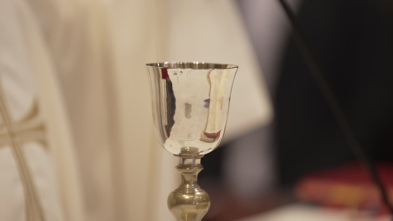 Silver chalice used in religious ceremonies, reflecting light and surroundings subtly