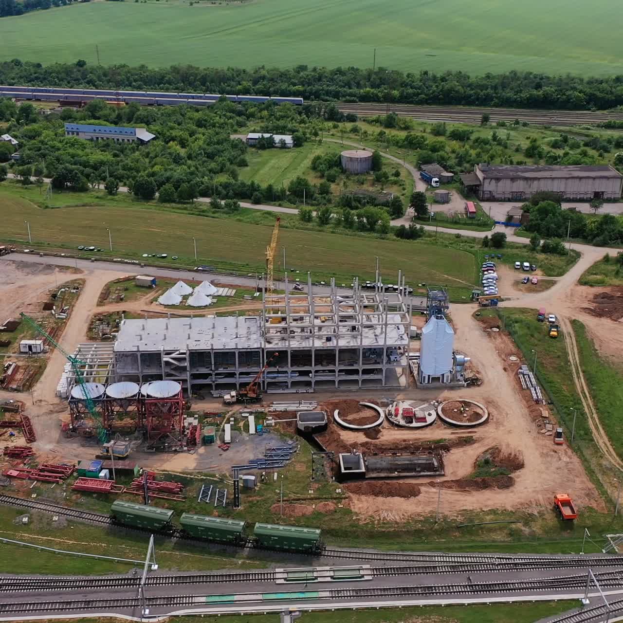 Construction site for the future silo grain complex. Vast territory with materials for construction. Green nature landscape at the background
