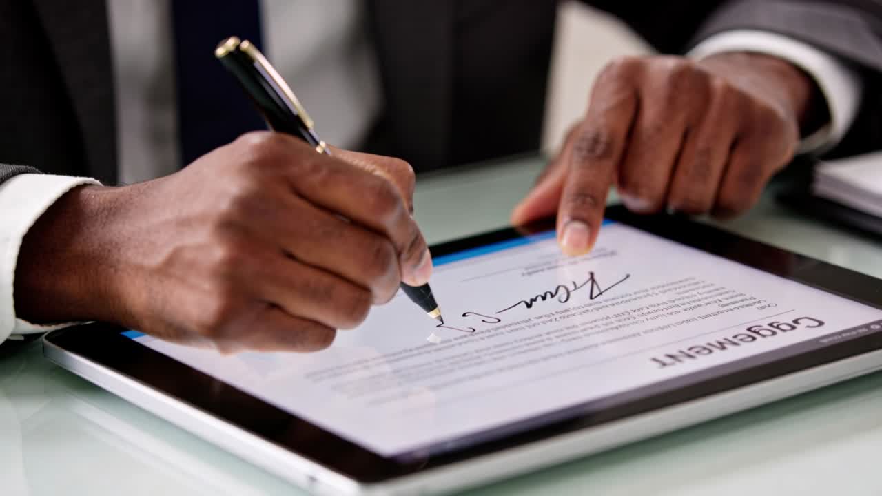 Business professional pointing left index finger, drawing signature on tablet to finalize contract