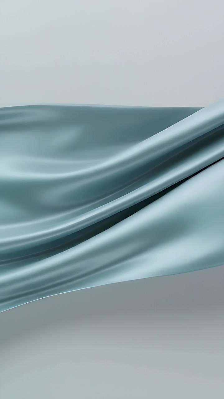 Vertical video: Sweeping pale blue silk fabric across gray studio backdrop, airflow creating motion
