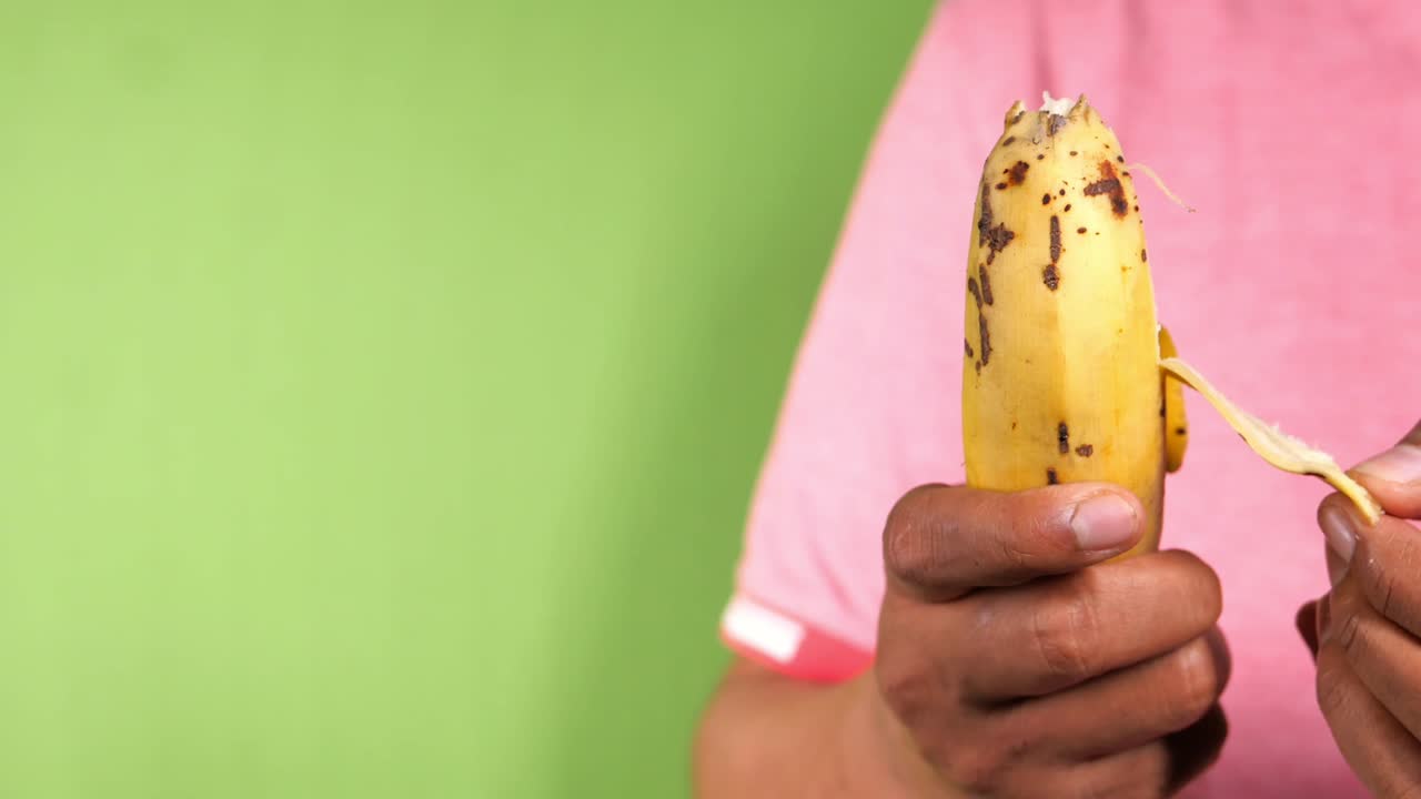 초록색 화면에서 질이 벗겨진 노란색 바나나를 들고 있는 손,