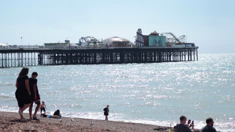 family walking along brighton beach near pier