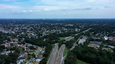 an aerial time lapse over the highway. it is a high angle shot, high enough to see the horizon and blue skies with white clouds. the drone camera moves forward along the highway, then tilts down