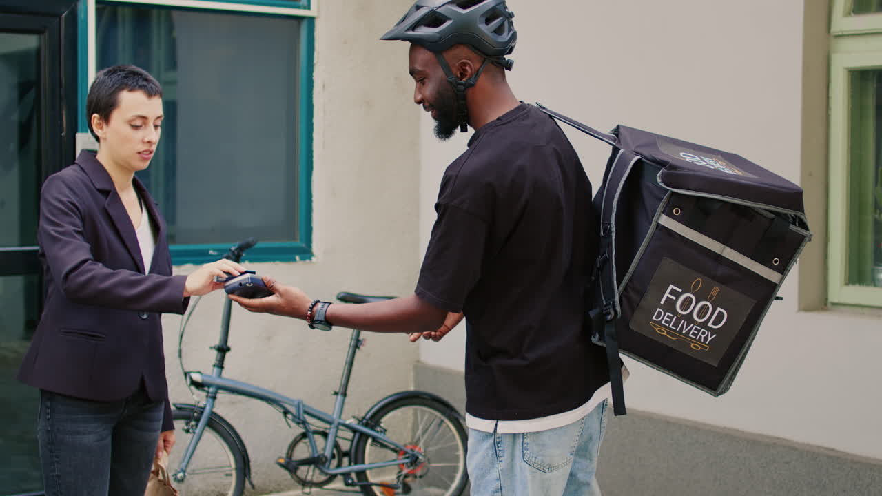 A food delivery courier gives a paper bag of food to a woman
