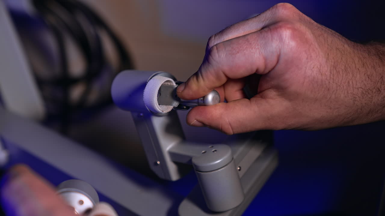 Surgeon's male hand shows the movement of a handle at operational equipment of Da Vinci machine. Man easily rotating the handles and presses buttons. Close up.