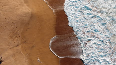 Drone-view-beautiful-sandy-beach-in-Portugal,-image-of-the-pattern-created-by-white-waves-hitting-the-shore