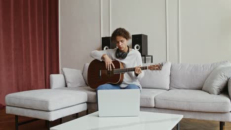 young man practicing guitar at home