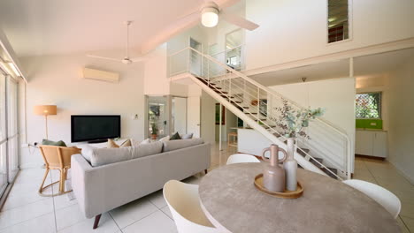 wide angle establish of urban elevated modern home house interior loungeroom with long staircase and tiled floor